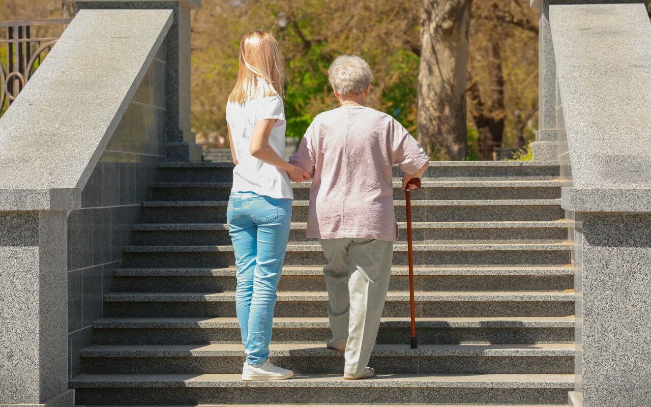 Carer helps elderly lady up steps