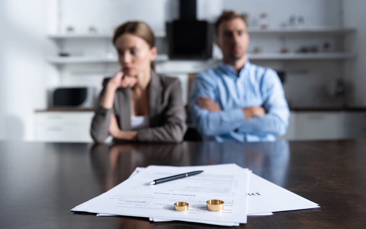 Divorced couple in front of rings & documents