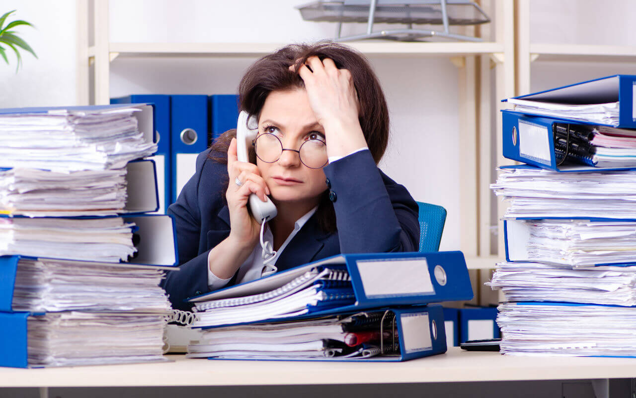 Woman at desk with excessive piles of litigation paperwork