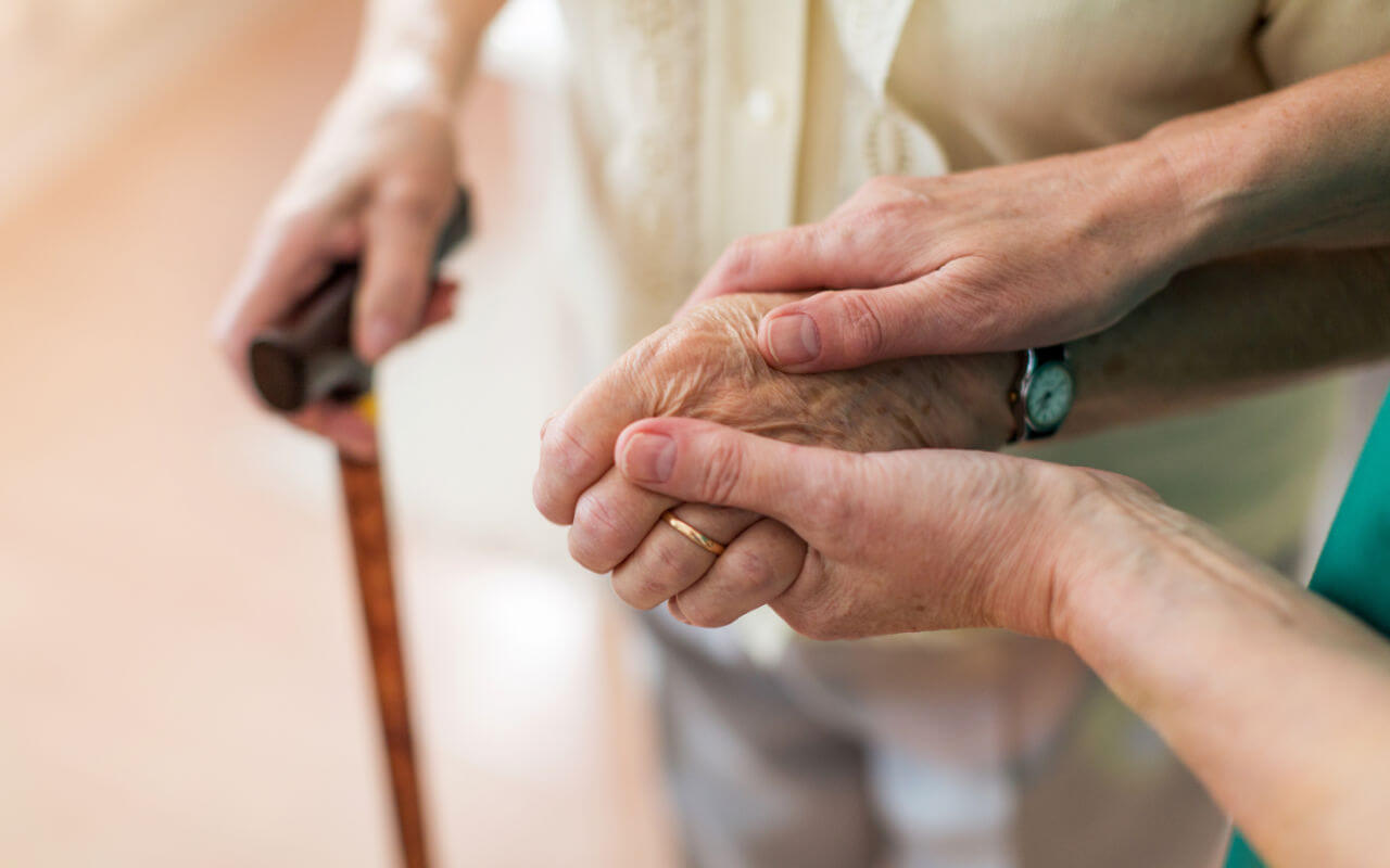 Elderly care dementia holding hands with cane