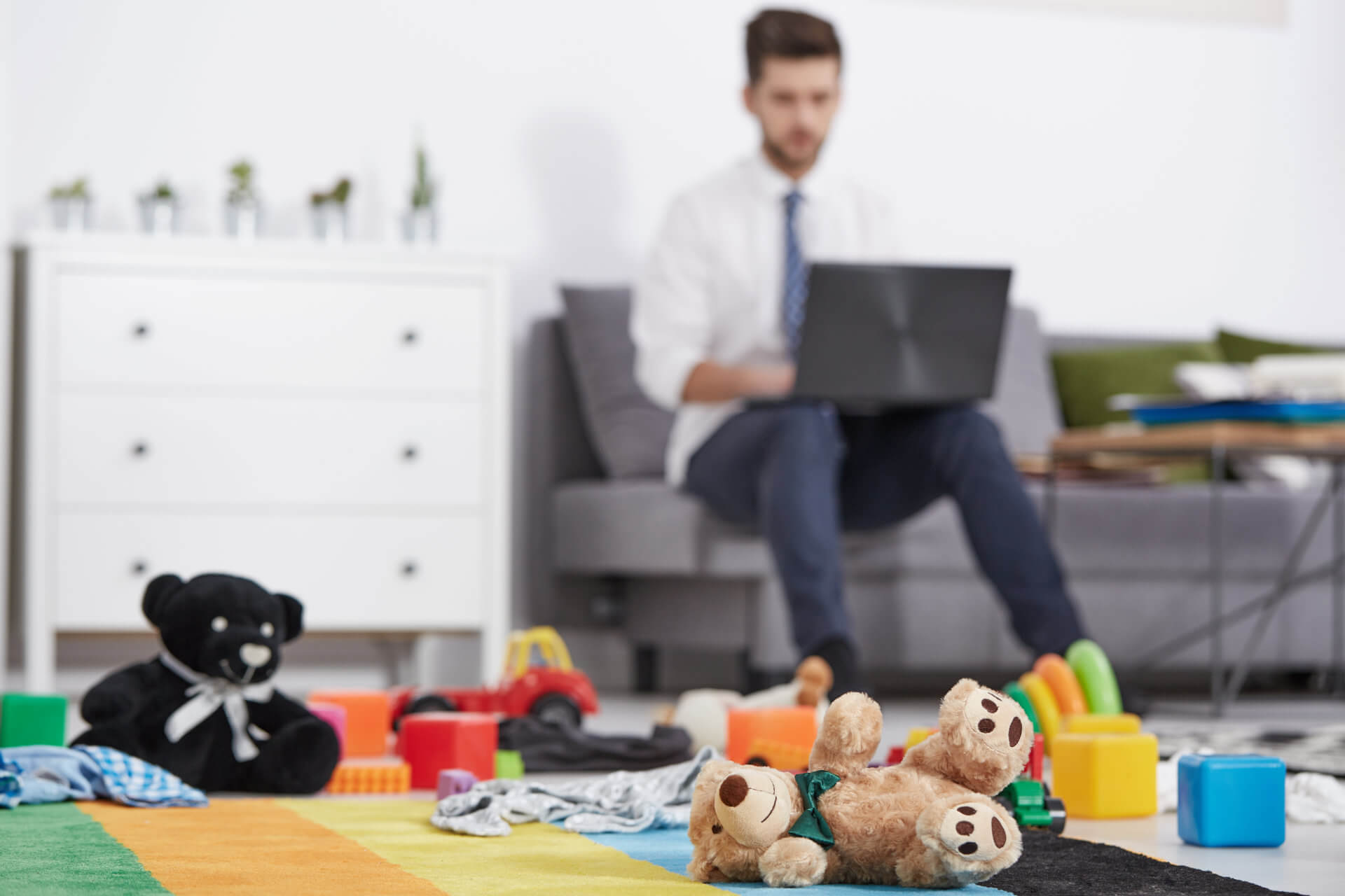 Work from home parental leave - man on laptop w/ children's toys