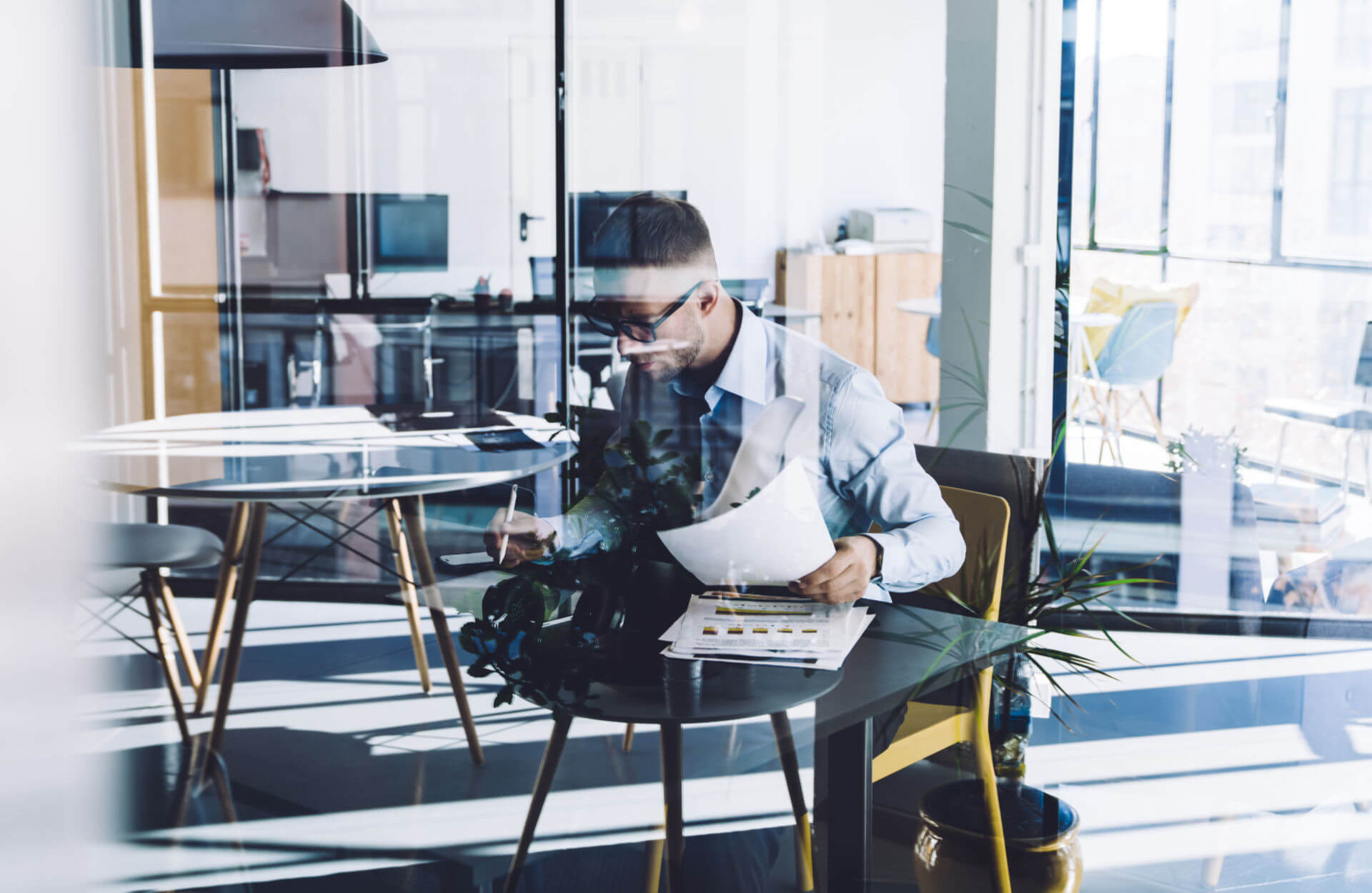 Man alone in office reads documents at table - High reflections