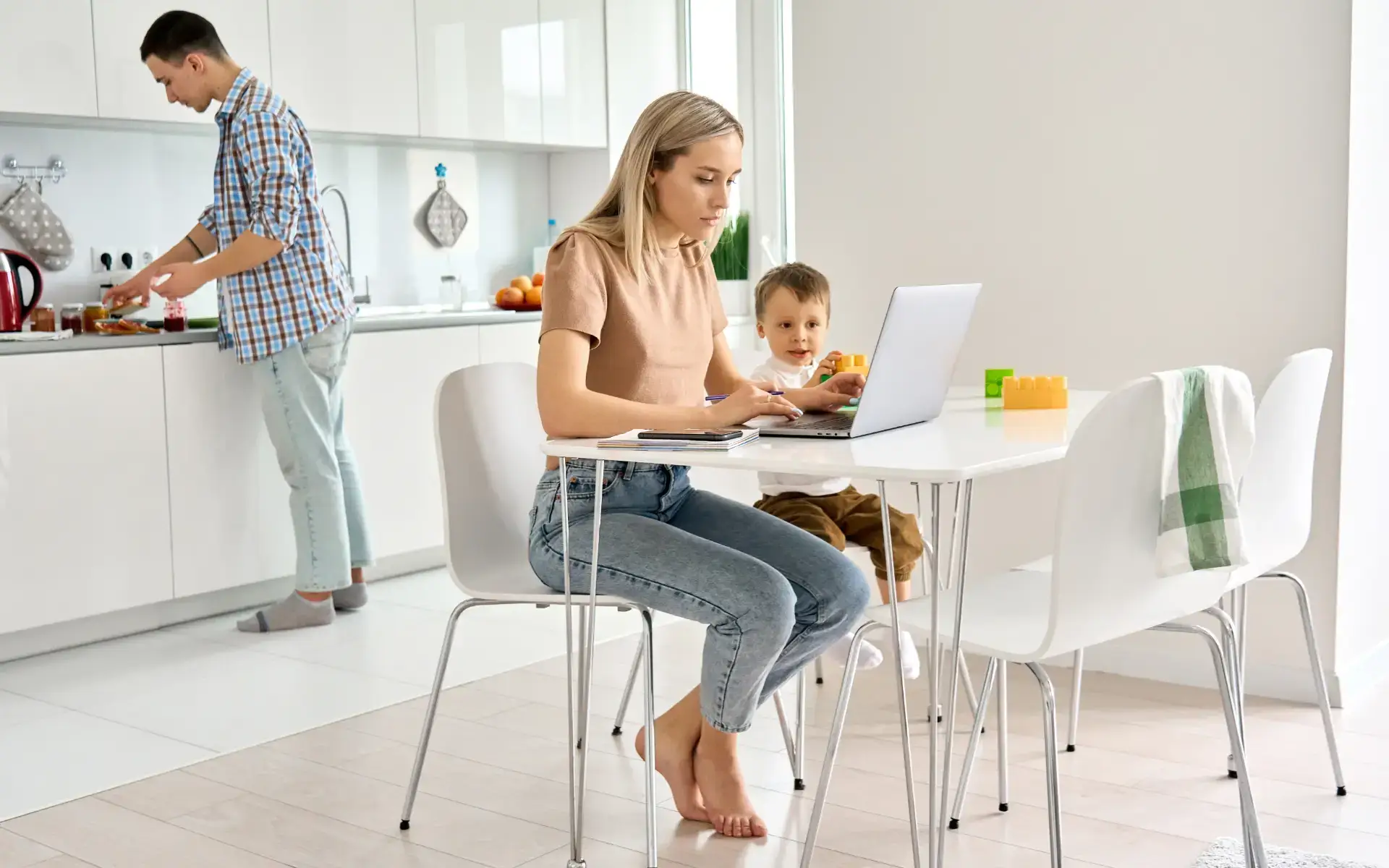 Family of mother father and baby in kitchen as mum works